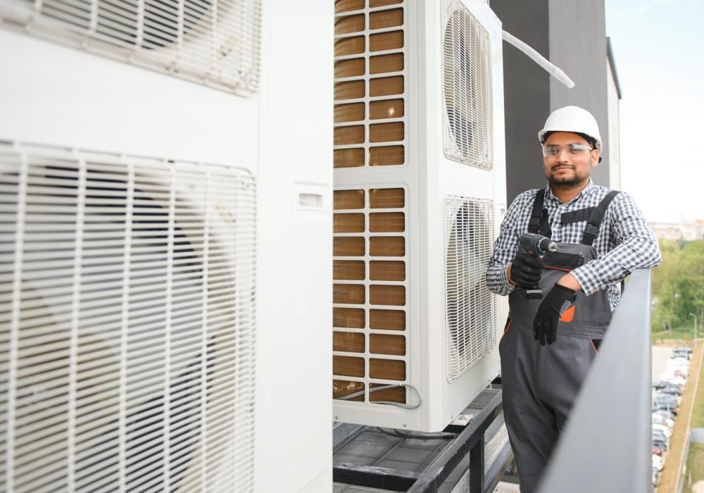 Repairman in uniform installing the outside unit of air conditioner