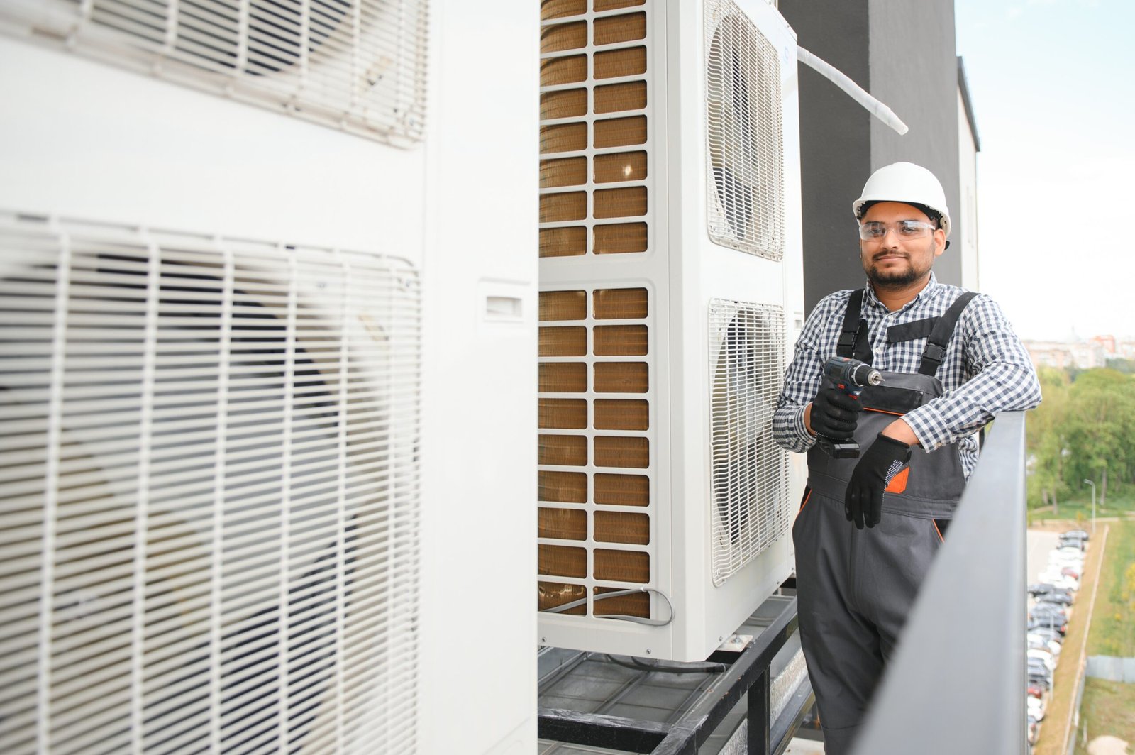Indian Repairman in uniform installing the outside unit of air conditioner Repairman in uniform installing the outside unit of air conditioner